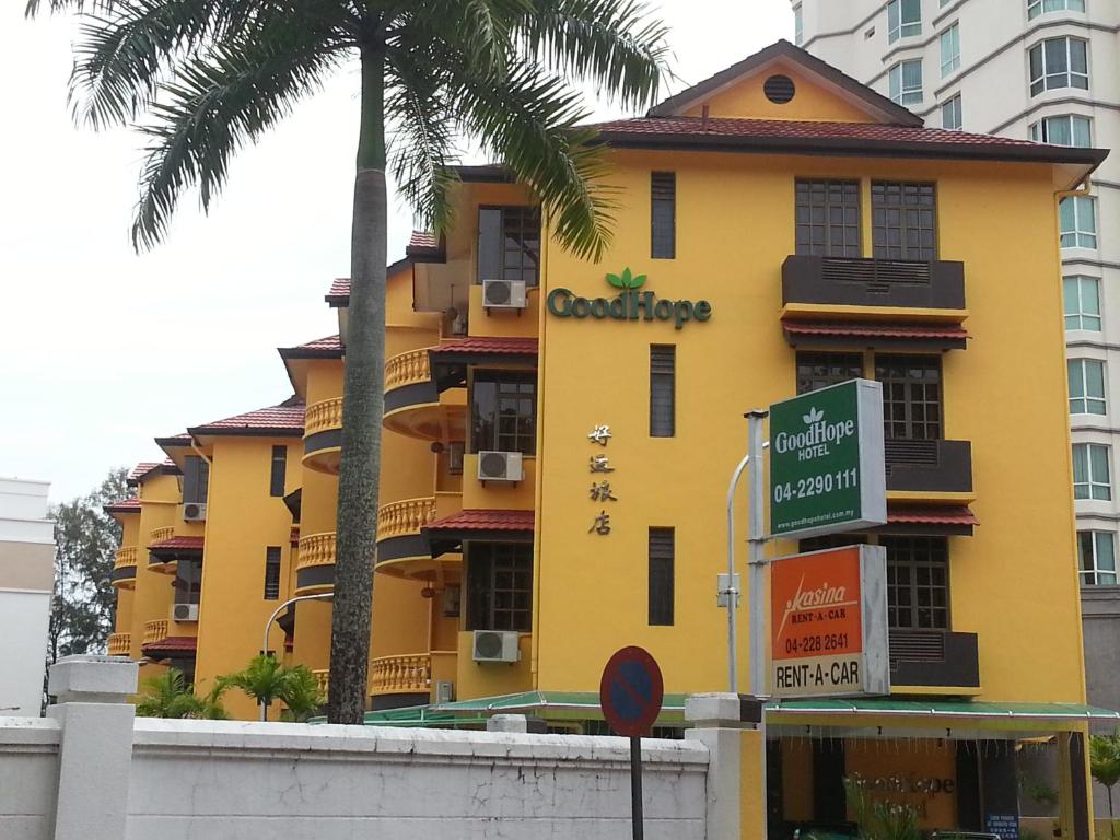 乔治市Goodhope Hotel Gurney, Penang的黄色的建筑,前面有标志