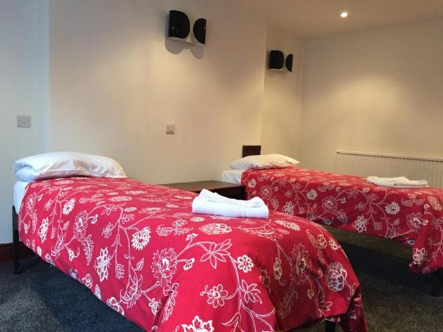伦敦四星级酒店的宿舍间的两张床,配有红色的床单和毛巾
