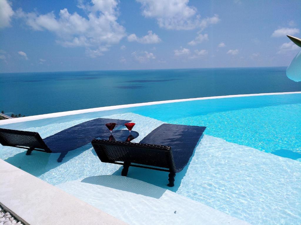 茶云莱海滩Villa Seawadee - luxurious, award-winning design Villa with amazing panoramic seaview的两把椅子坐在一个海洋游泳池旁