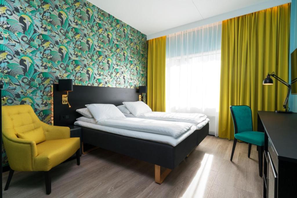 利勒斯特罗姆同恩运动场酒店的一间卧室配有一张床和一张黄色椅子