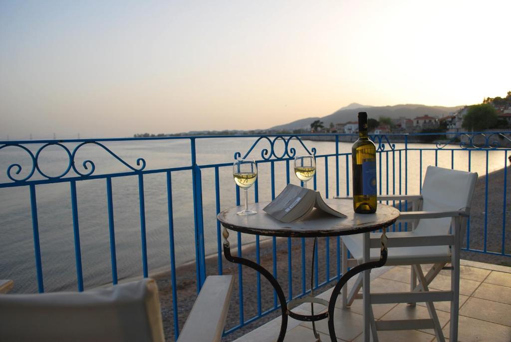纳弗帕克托斯Villa "Pietra e Mare"的阳台上的桌子和两杯葡萄酒