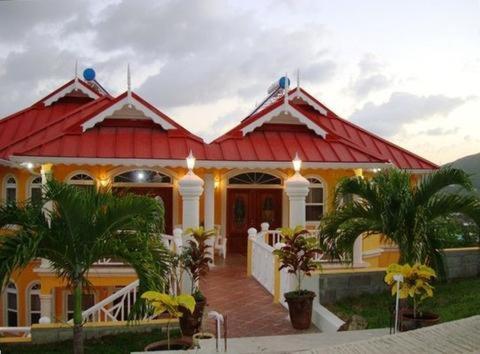 格罗斯岛Paradise Cove的一座红色屋顶和棕榈树的房子