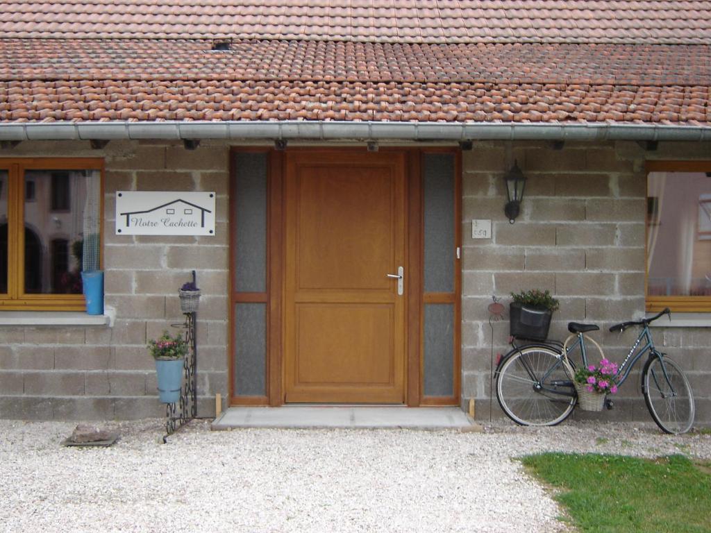 BiffontaineNotre Cachette的一辆停在房子前面的自行车,房子有木门