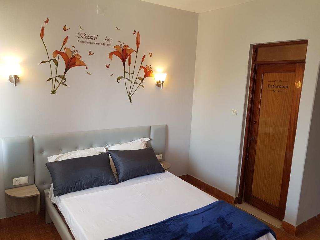 AssomadaPensão Asa Branca的卧室配有一张墙上鲜花的床