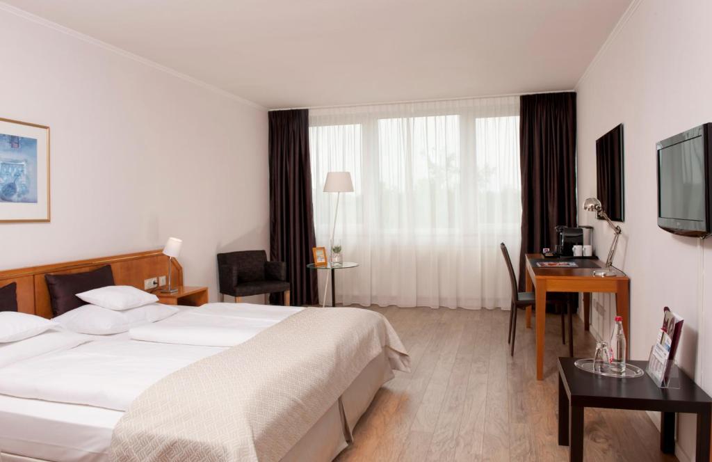 汉诺威温德姆汉诺威庭酒店的一间卧室配有一张床、一张书桌和一台电视