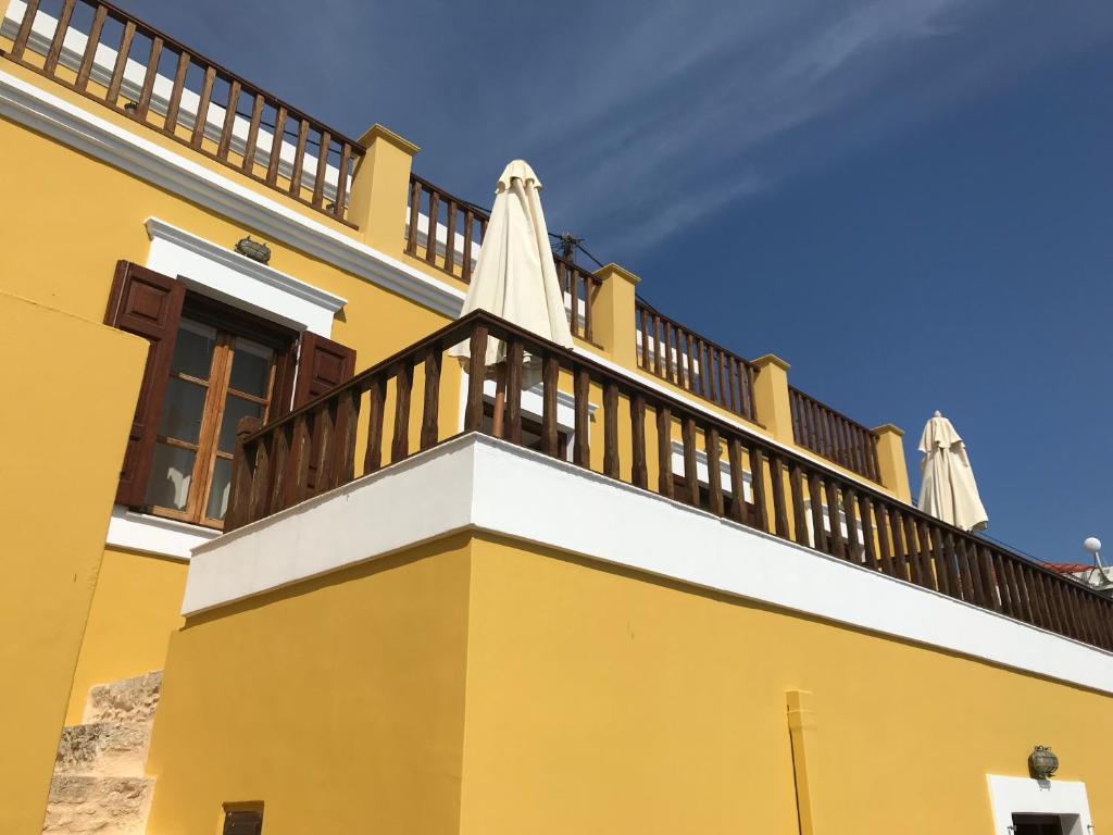 哈尔基岛Villa Amalia的黄色的建筑,阳台上配有遮阳伞