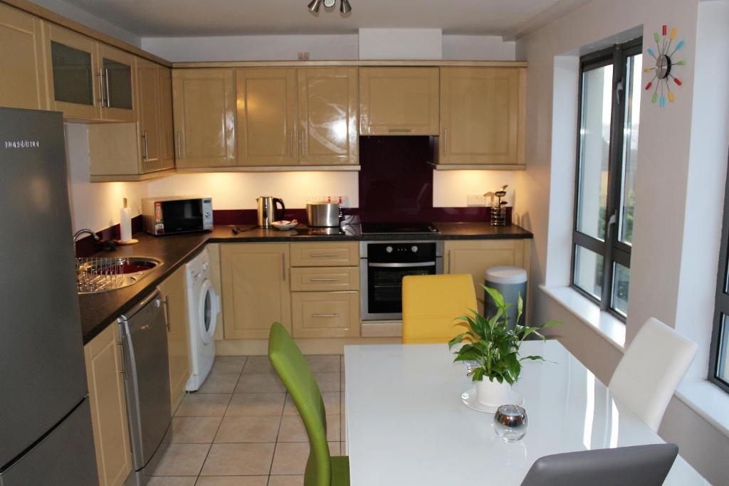 莱特肯尼Wild Atlantic Accommodation 18 Glenveagh Court的厨房配有木制橱柜和白色桌子。