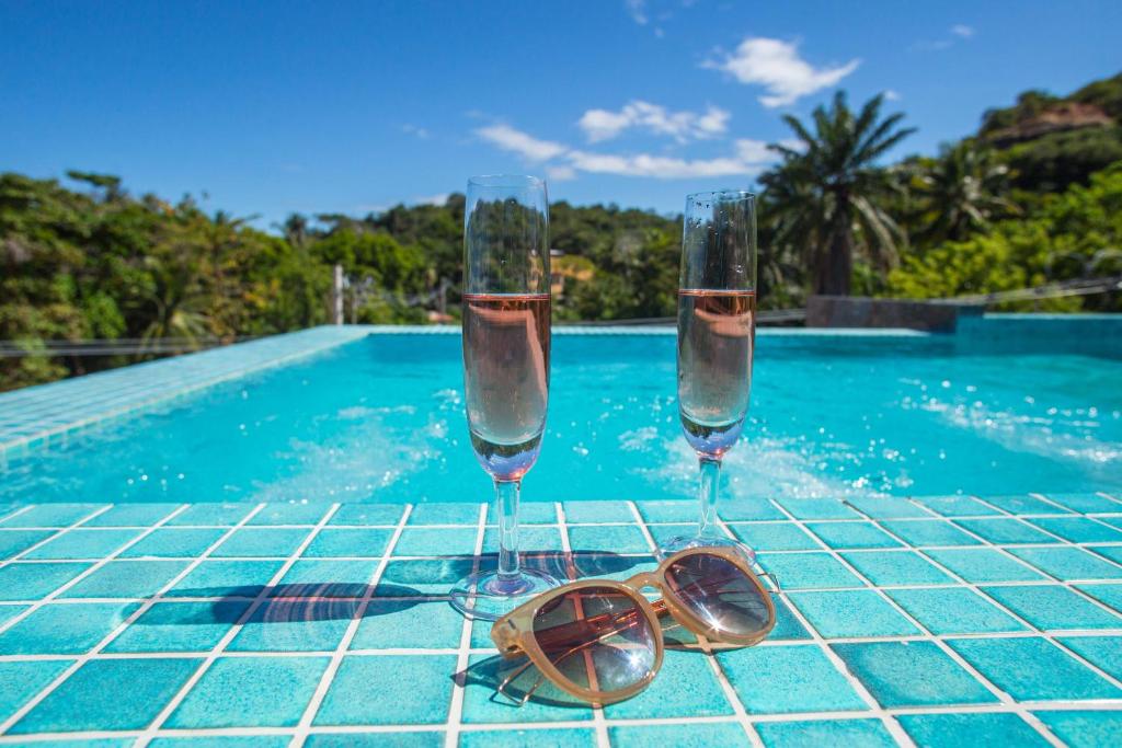 莫罗圣保罗Pousada Renda do Mar的游泳池畔桌子上放上两杯眼镜和太阳镜