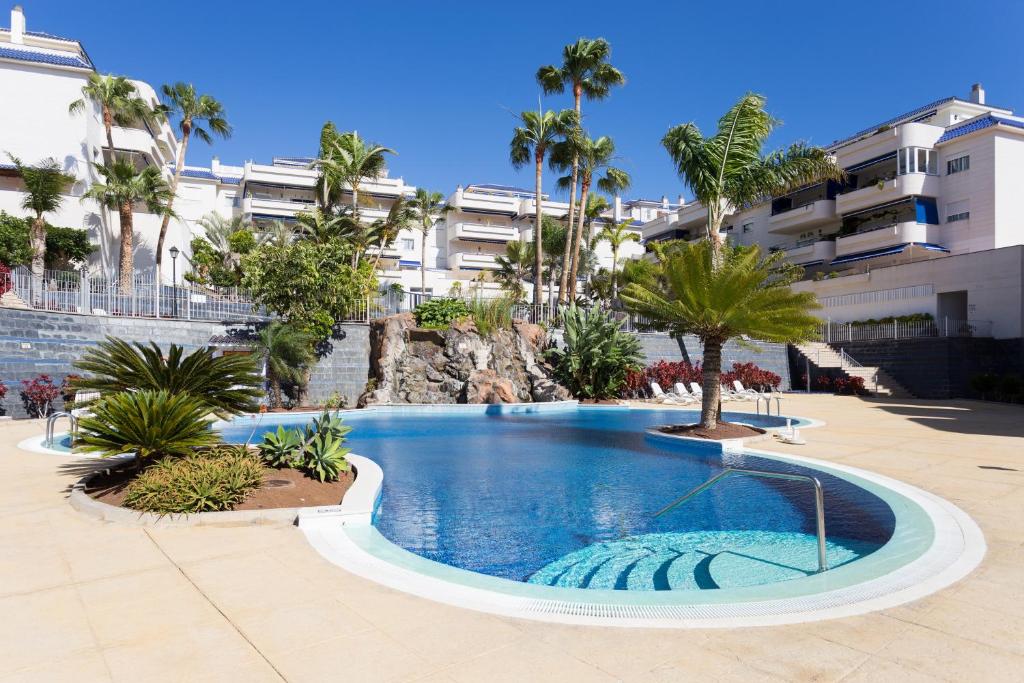 洛斯克里斯蒂亚诺斯El Ancla的棕榈树和建筑度假村内的游泳池