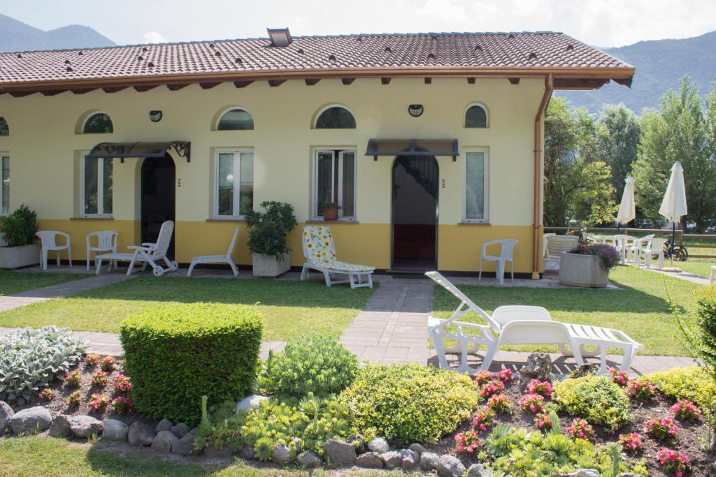 Ponte CaffaroCasa Ornella的黄色房屋,配有椅子和花园