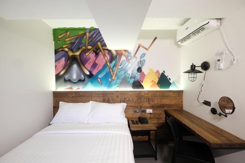 马尼拉马卡蒂U酒店的一间卧室配有一张床和一张墙上画的桌子