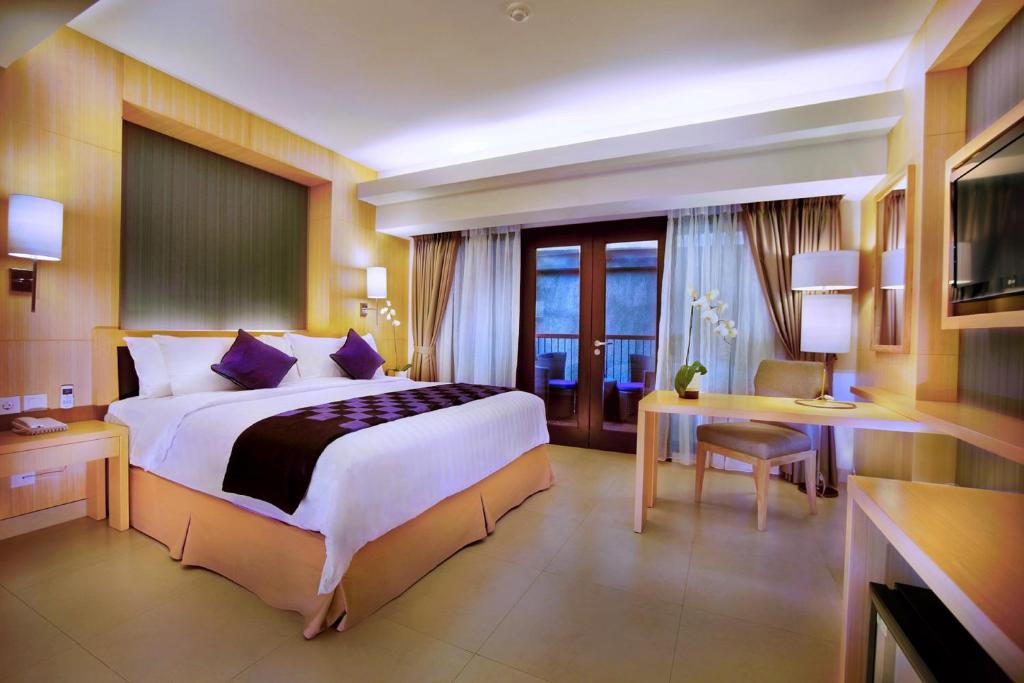 库塔Quest Hotel Kuta by ASTON的酒店客房设有一张大床和一张书桌。
