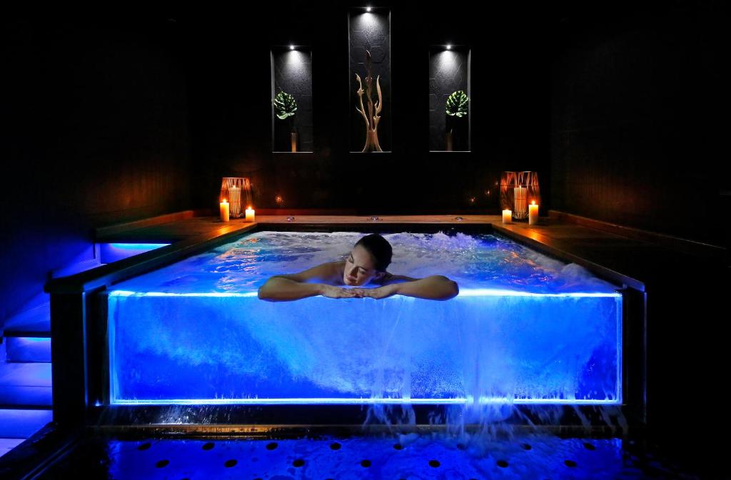 普罗旺斯艾克斯Negrecoste Hôtel & Spa的躺在蓝色水的热水浴缸中的女人