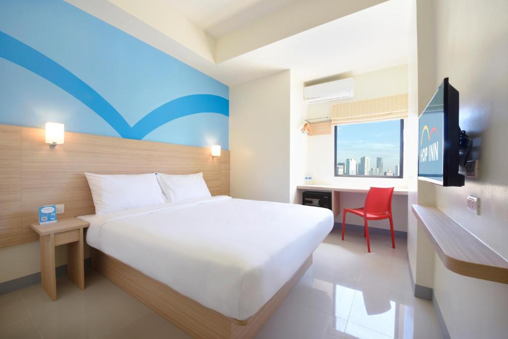 马尼拉Hop Inn Hotel Aseana City Manila的卧室配有一张白色大床和红色椅子