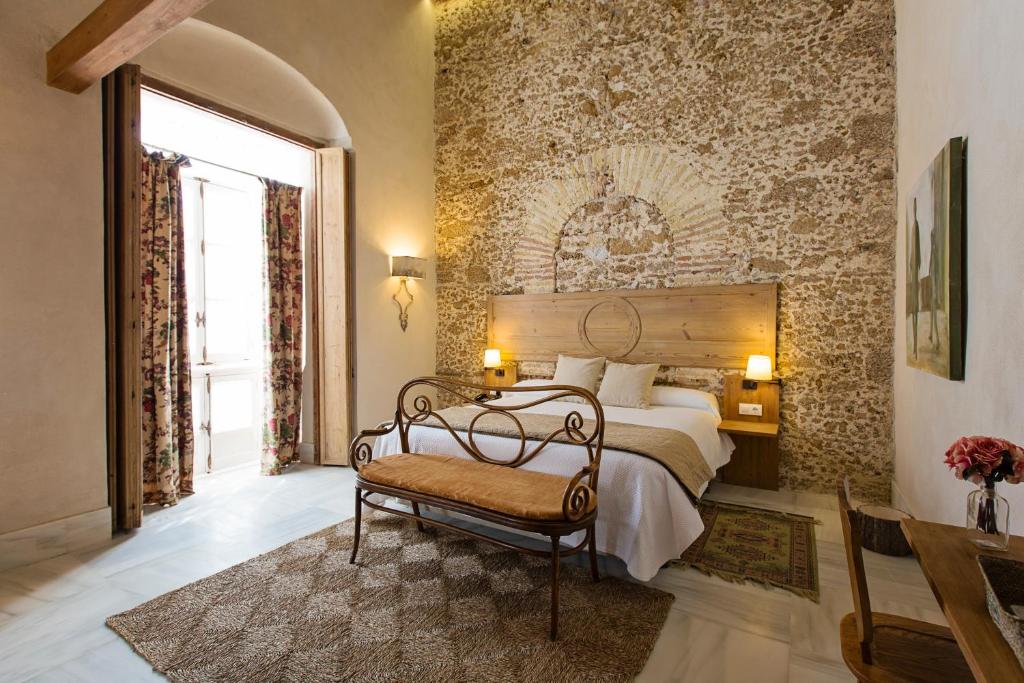 加的斯Hotel Casa de las Cuatro Torres的一间卧室配有一张床,卧室配有长凳