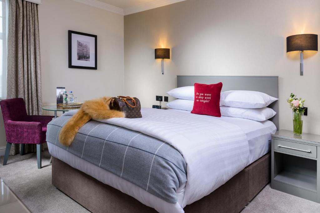 科克The Metropole Hotel Cork的酒店客房配有一张带红色枕头的大床