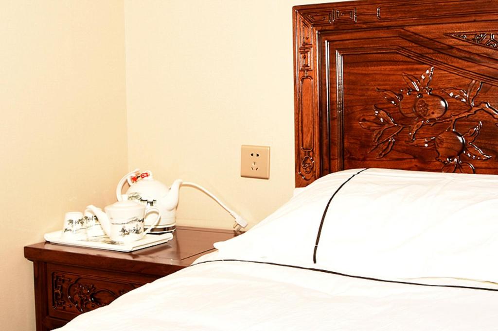 密云古北水镇东篱民宿四合院的一间卧室配有一张带木制床头板和床头柜的床。