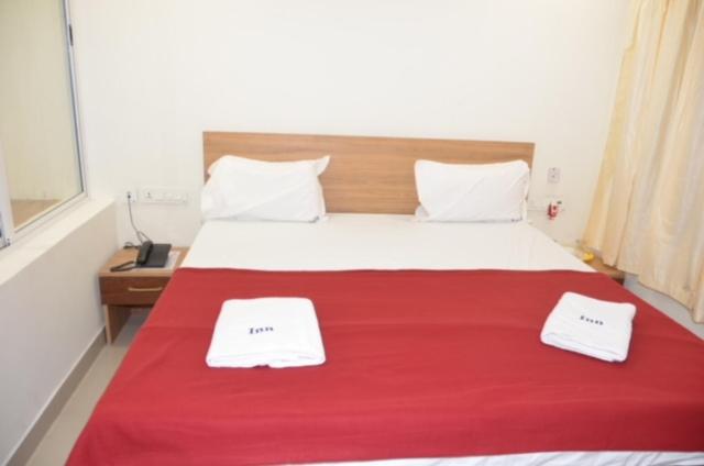 库姆巴科纳姆Raya's Inn的一间卧室配有红色的床和2条毛巾