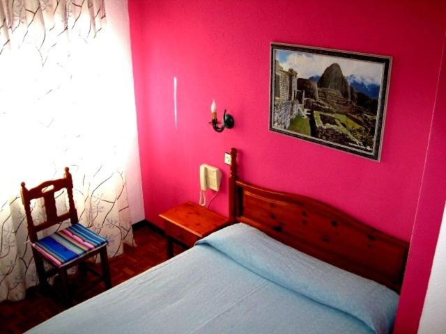 萨拉曼卡库斯科旅馆的粉红色的卧室配有床和椅子