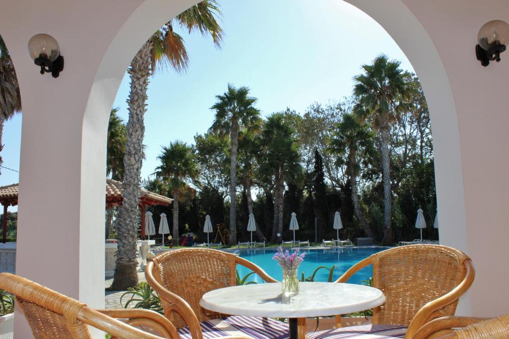 科斯镇安德洛墨达公寓式酒店的一个带桌椅的庭院和一个游泳池