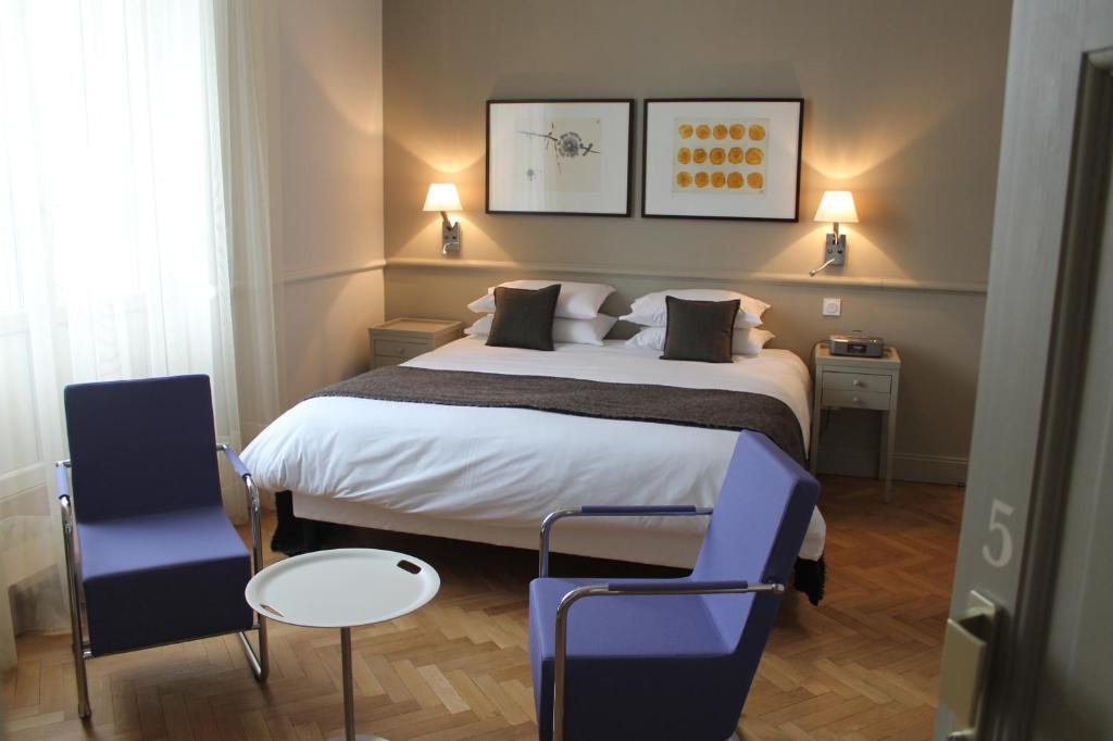 科尔马艾琳别墅酒店的一间卧室配有一张大床和一张蓝色椅子