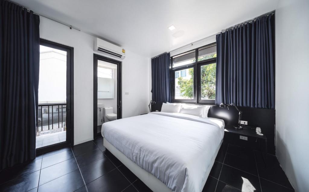 清迈The Common Hostel的卧室配有白色的床和2扇窗户。