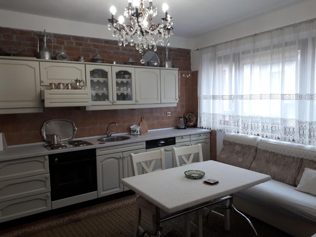 维索科Apartment Sun的厨房配有白色橱柜、桌子和吊灯。