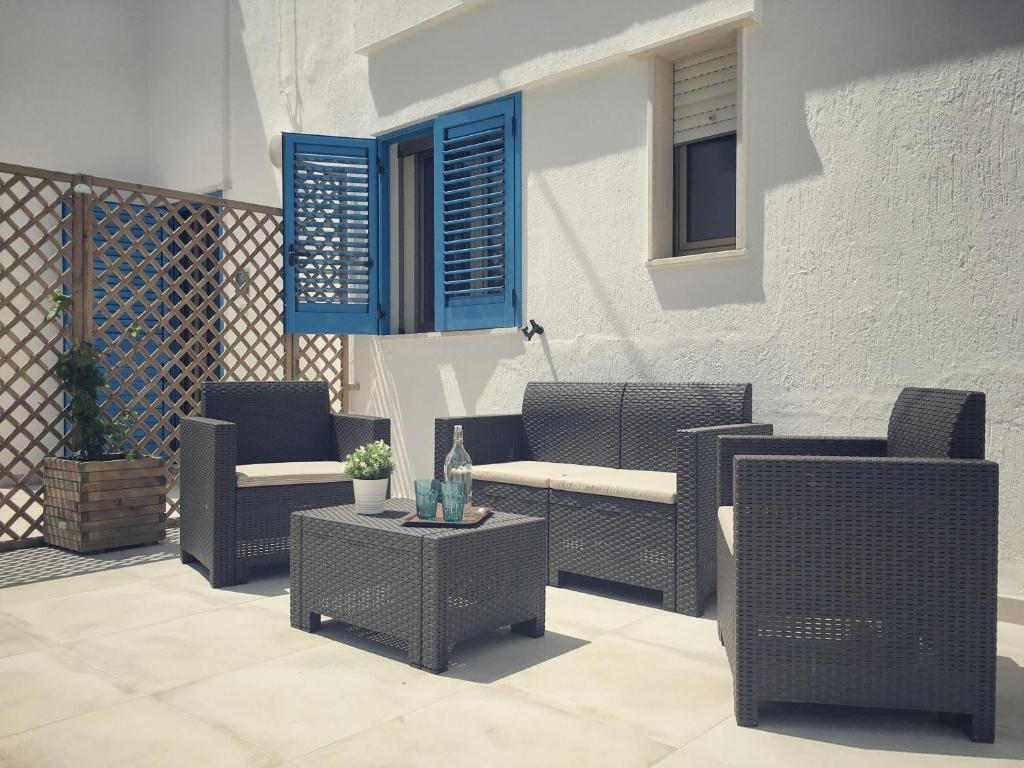 丽都玛里尼SoleMareSalento Pt的庭院设有藤椅、桌子和蓝色窗户。