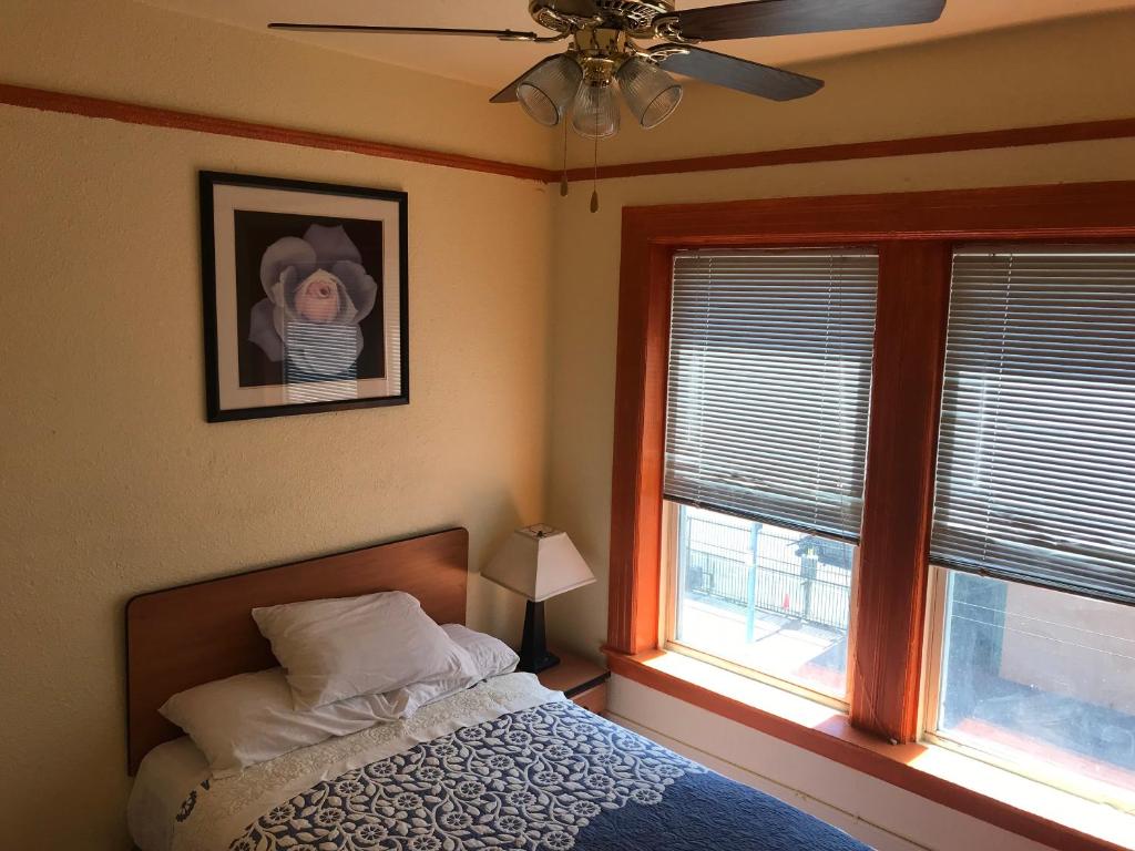 旧金山波士顿酒店 的一间卧室配有一张带风扇的床和两个窗户。