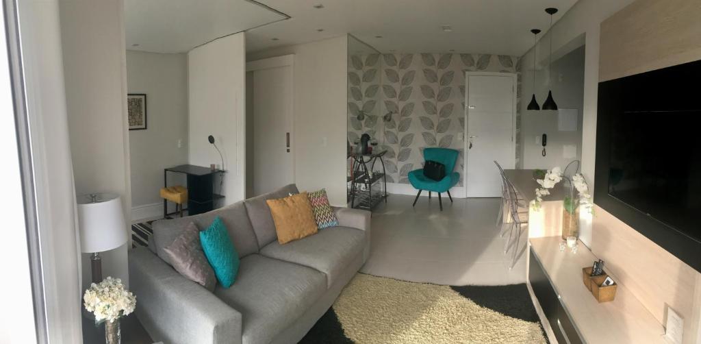 圣保罗Apartamento Menara Morumbi的客厅配有灰色的沙发和蓝色的椅子