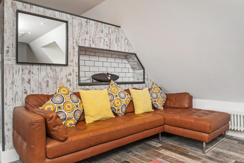 温彻斯特Paddock View的客厅里配有棕色皮沙发及黄色枕头