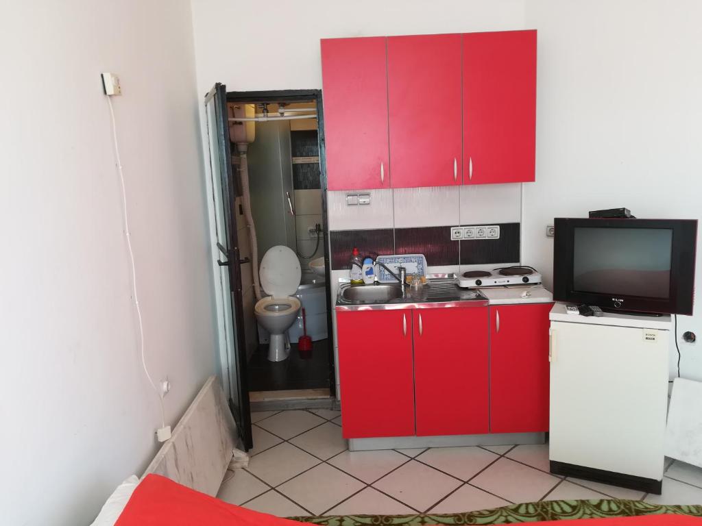 克拉多沃Apartmani Filipovic的一间带红色橱柜和电视的小厨房