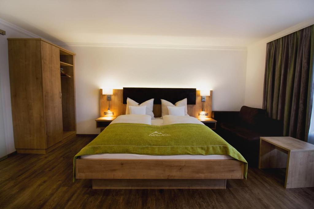 鲁波尔丁Hotel Alp Inn的一间卧室配有一张带绿毯的大床