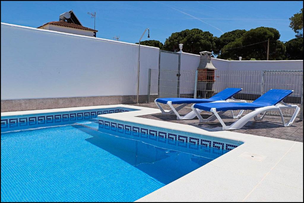 科尼尔-德拉弗龙特拉Casa Rural Zara II的一个带两把蓝色椅子的游泳池,围栏旁
