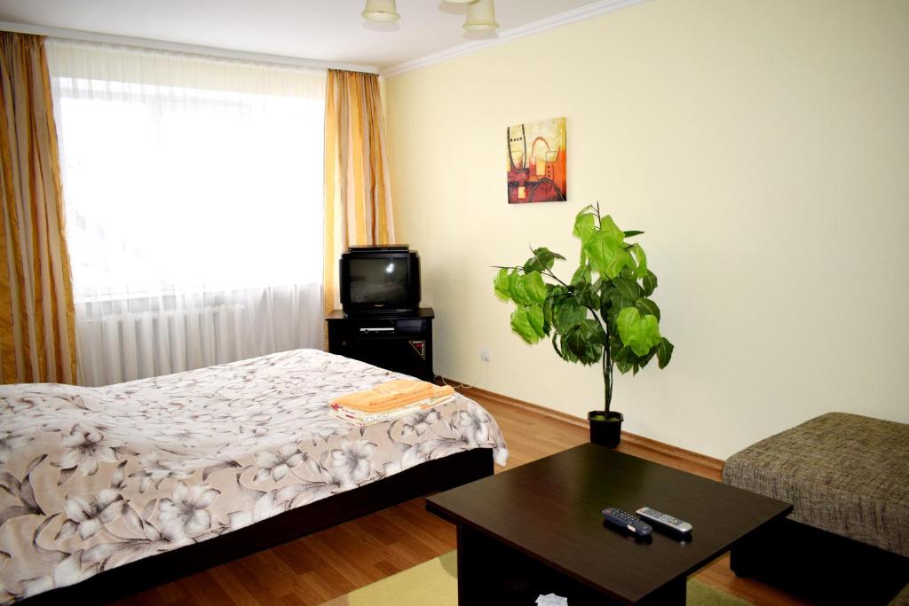 罗夫诺Apartment on Krushelnitskoy 73的一间卧室配有一张床、一台电视和一张桌子