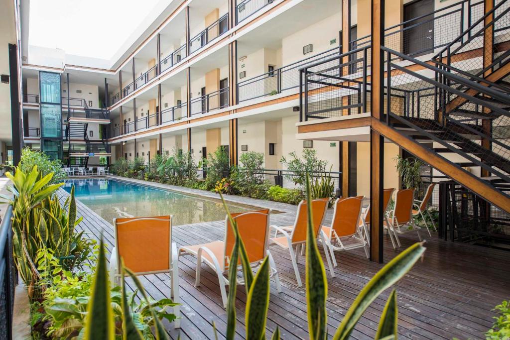 图斯特拉古铁雷斯Hotel Andiroba Palace的公寓大楼设有游泳池和橙色椅子