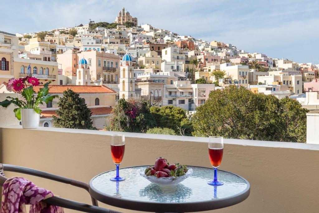 埃尔莫波利斯伊利亚达酒店的阳台上的桌子上放着两杯酒和一碗水果