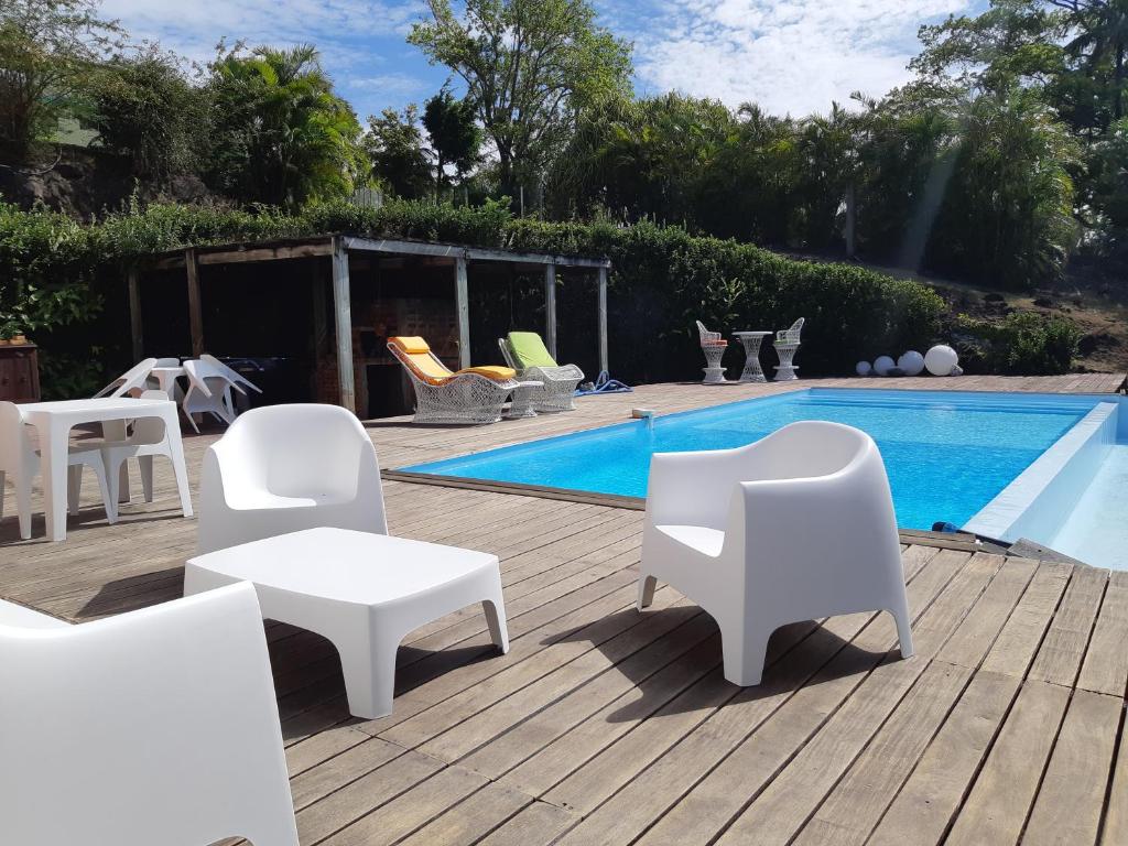德赛Domaine Choco Vanille的一个带白色椅子的庭院和一个游泳池