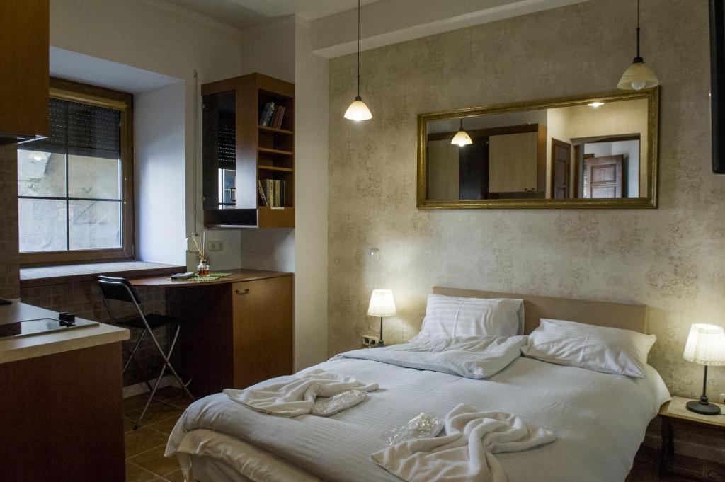 维尔纽斯纳塔雷克​​斯公寓式酒店的一间卧室配有一张带白色床单和镜子的床