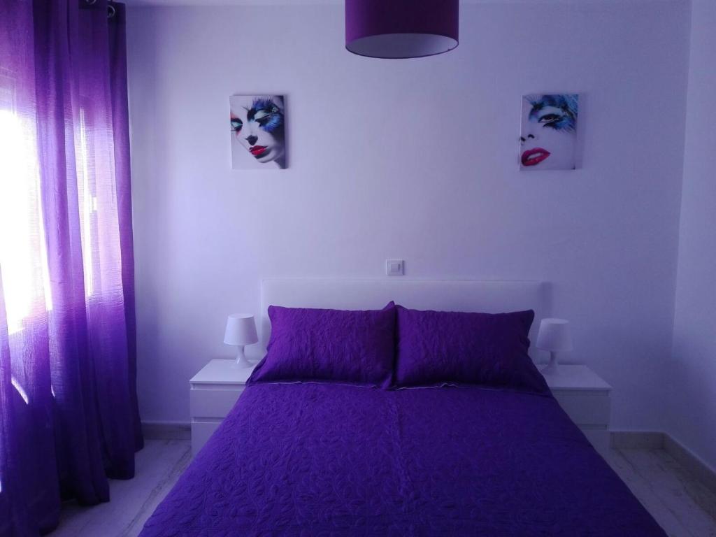 本迪亚Apartamento Altomira的卧室配有一张紫色床,墙壁上有两个面孔