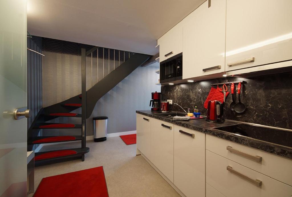 舍纳贝克Ferienhof Elbaue的厨房配有白色橱柜和黑色楼梯
