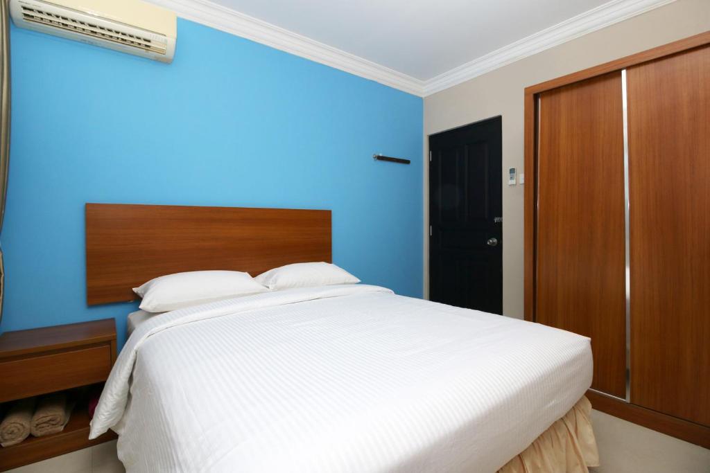 瑟古邦瑟古邦巴淡岛萨芬娜旅馆的一间卧室配有一张白色大床和蓝色的墙壁