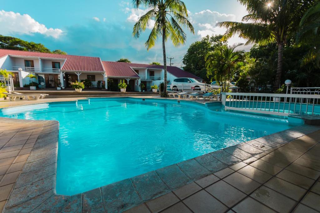 蒙舒瓦西Residence Villas Mont Choisy的棕榈树屋前的游泳池
