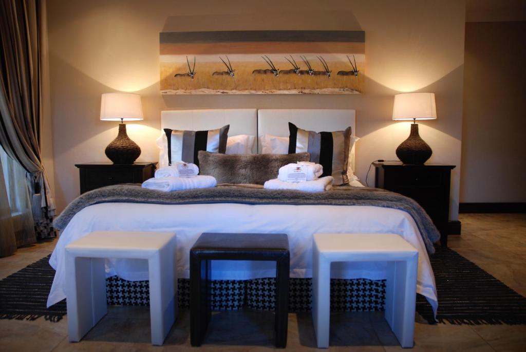 卡图Kathuhari Guesthouse的一间卧室配有一张带两张凳子和两盏灯的床。