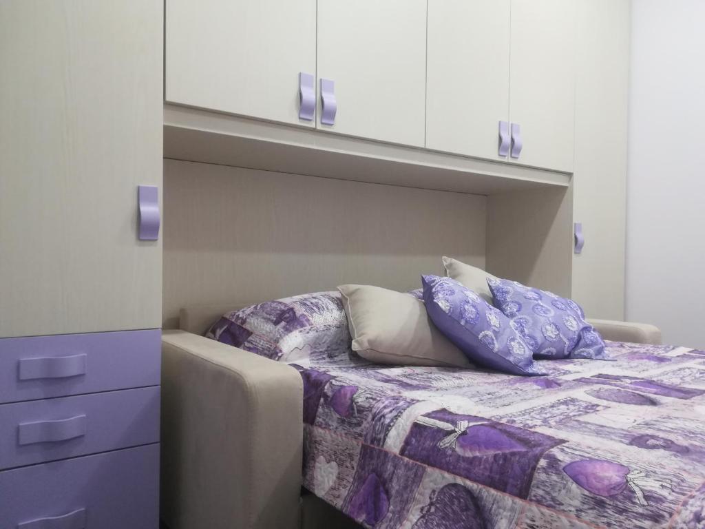 陶尔米纳Attico Sole Luna的一间卧室配有一张带紫色床单和白色橱柜的床。