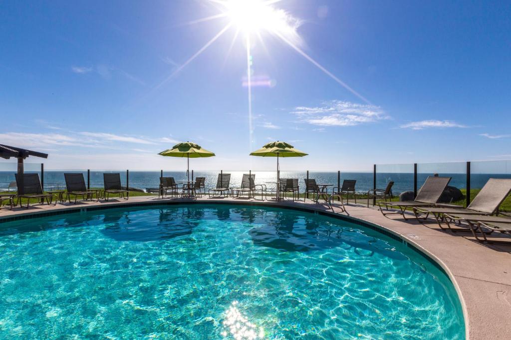 圣地亚哥Wave Crest Resort的一座大楼的顶部,设有一座带椅子和遮阳伞的游泳池