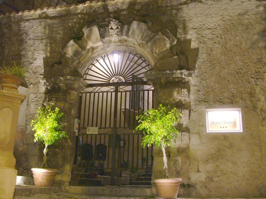 莫迪卡Hotel Relais Modica的石头建筑中的一个门,有两株盆栽植物