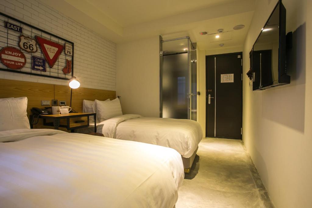 台北台北旅‧晨行旅的酒店客房设有两张床、一张桌子和一扇门。