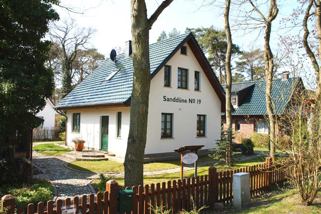 博尔滕哈根Ferienhaus "Sanddüne No.19"的白色的房子,有黑色的屋顶和栅栏