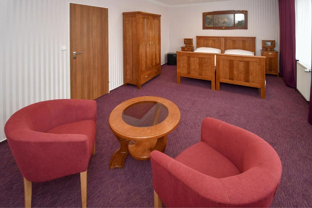 摩拉维采河畔赫拉德茨Hotel Sonata的一间设有两把椅子、一张桌子和一张床的房间